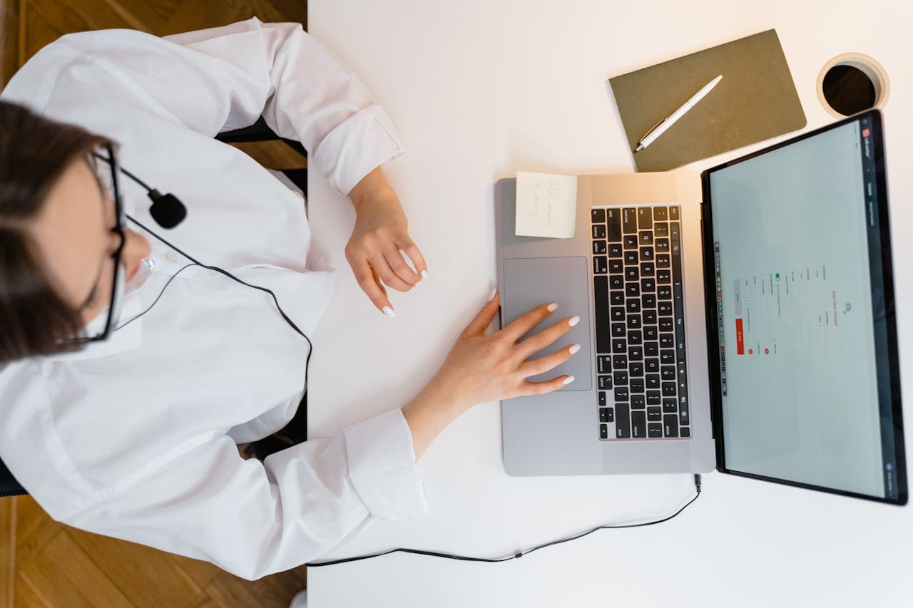 A call center agent wearing a headset works on her laptop in a bright, modern office.